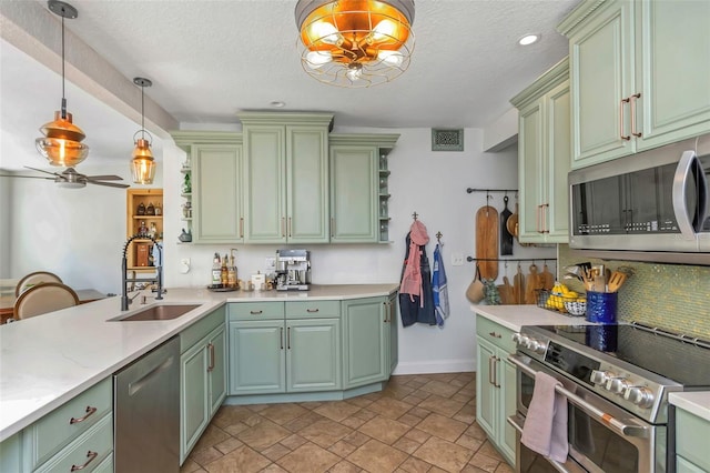 kitchen with green cabinetry, appliances with stainless steel finishes, light countertops, and a sink