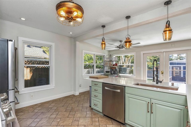 kitchen featuring a ceiling fan, a sink, stainless steel appliances, green cabinetry, and baseboards