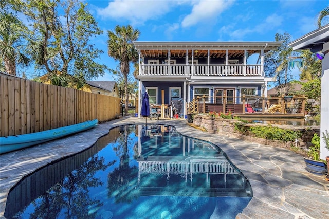 back of house featuring a patio area, a balcony, a fenced backyard, and a fenced in pool