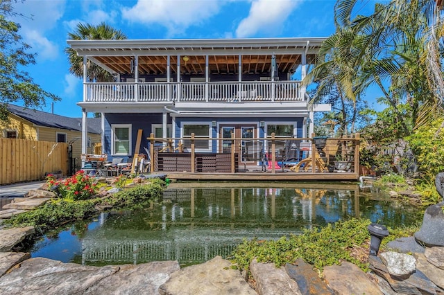 back of house featuring a wooden deck, a garden pond, a balcony, and fence