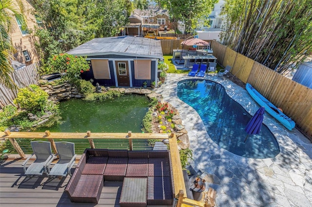 view of swimming pool with a fenced backyard, a wooden deck, a fenced in pool, and an outdoor structure