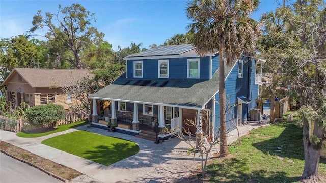 view of front of home with driveway, a front lawn, a porch, a shingled roof, and solar panels