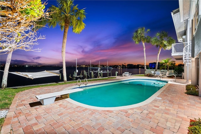 520 Belle Isle Ave, Belleair Beach, FL 33786 - pool at dusk with fence, a fenced in pool, a diving board, a water view, and a patio area