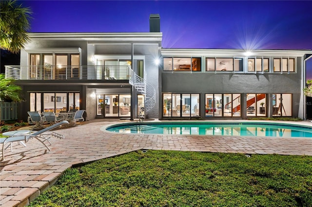 520 Belle Isle Ave, Belleair Beach, FL 33786 - rear view of house featuring stucco siding, stairway, an outdoor pool, a balcony, and a patio area