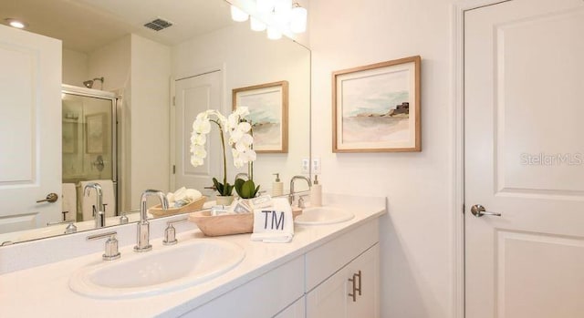 full bath with double vanity, visible vents, a stall shower, and a sink