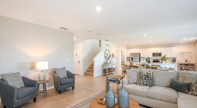 living area with visible vents, baseboards, stairway, light tile patterned floors, and recessed lighting