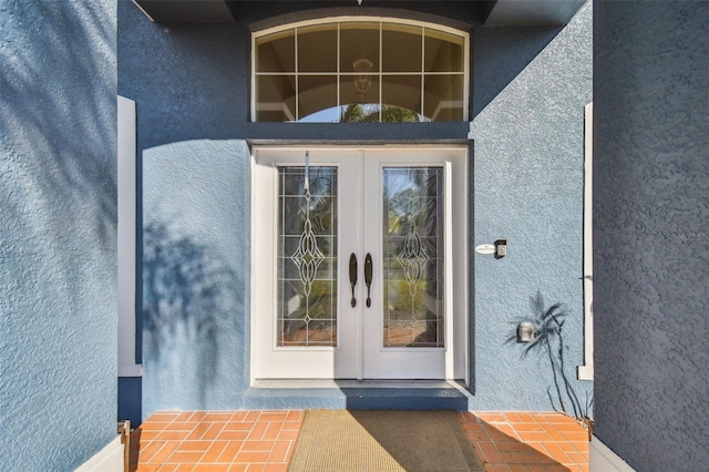 view of exterior entry with stucco siding and french doors