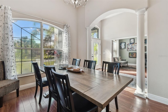 dining area featuring arched walkways, dark wood-style floors, baseboards, and ornate columns