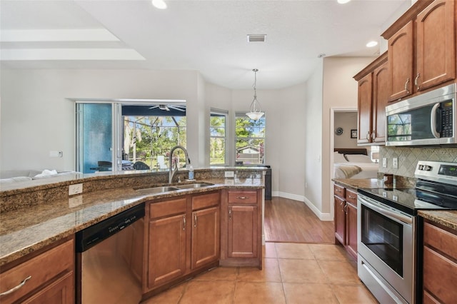 kitchen with visible vents, stone countertops, a sink, stainless steel appliances, and backsplash