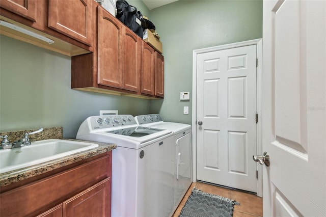 clothes washing area featuring a sink, light tile patterned floors, cabinet space, and washing machine and clothes dryer