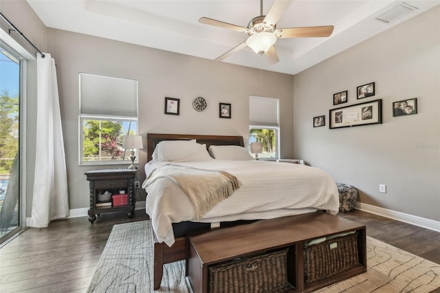 bedroom featuring dark wood finished floors, baseboards, visible vents, and a ceiling fan