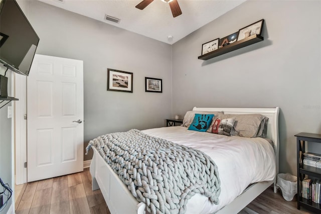 bedroom with visible vents, baseboards, ceiling fan, and wood finished floors