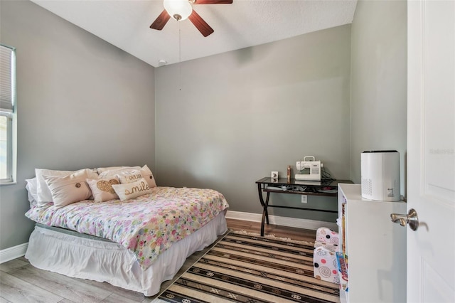 bedroom with ceiling fan, baseboards, and wood finished floors