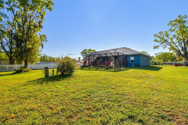 view of yard with glass enclosure and fence