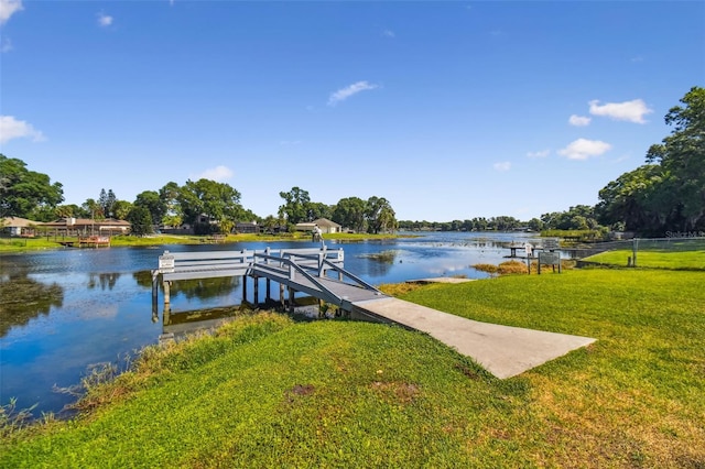 view of dock with a lawn and a water view