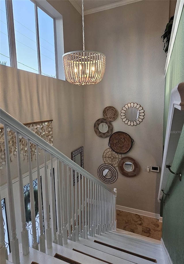 staircase with baseboards, a chandelier, and crown molding