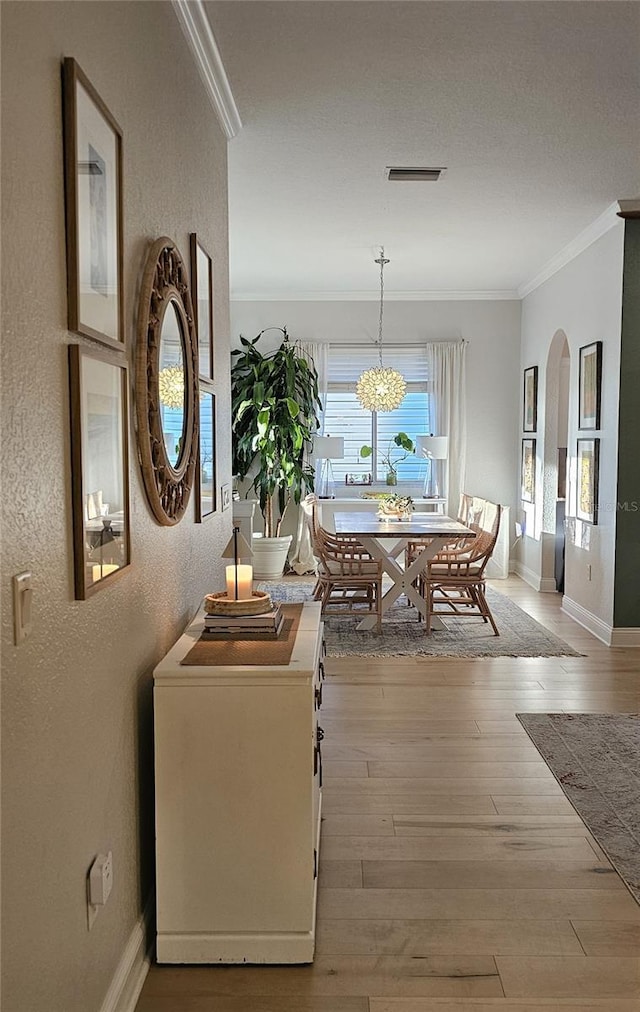 dining space with arched walkways, visible vents, crown molding, and wood finished floors