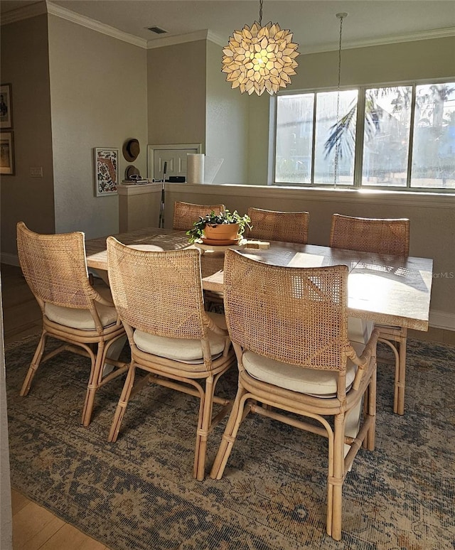 dining area with wood finished floors and ornamental molding