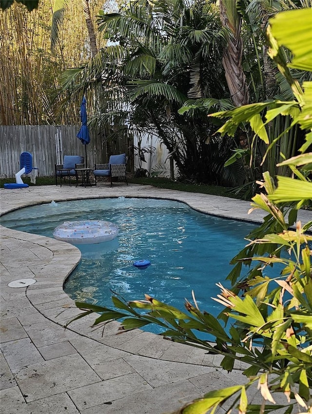 view of swimming pool with a fenced in pool, a fenced backyard, and a patio area