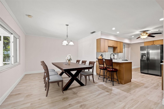 dining room with visible vents, light wood-style floors, baseboards, and ornamental molding