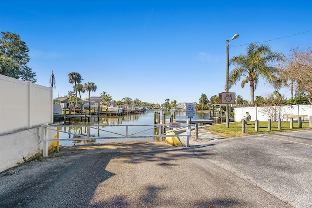 view of dock with a water view, boat lift, and fence