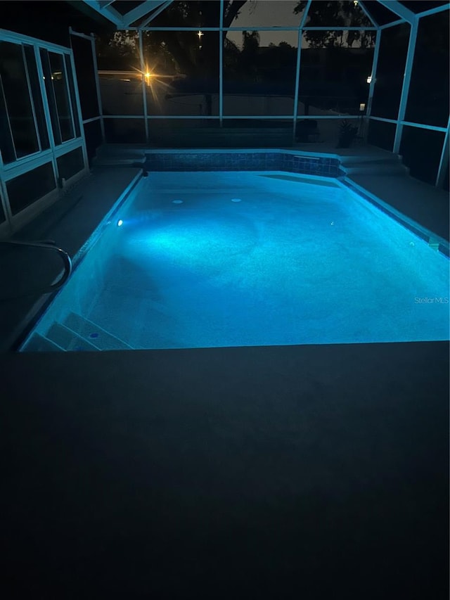 pool featuring glass enclosure and a patio