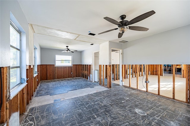 interior space featuring a wainscoted wall, visible vents, and a ceiling fan