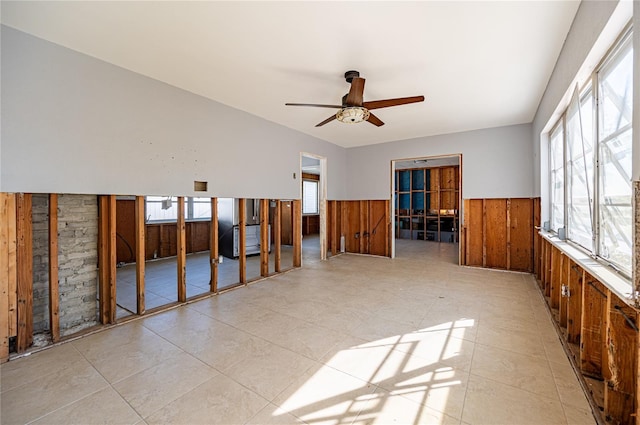 spare room featuring a wainscoted wall, wood walls, and a ceiling fan