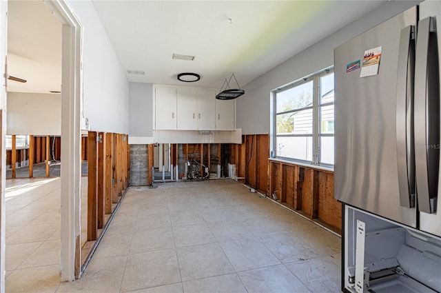 kitchen featuring visible vents, white cabinetry, freestanding refrigerator, wood walls, and wainscoting