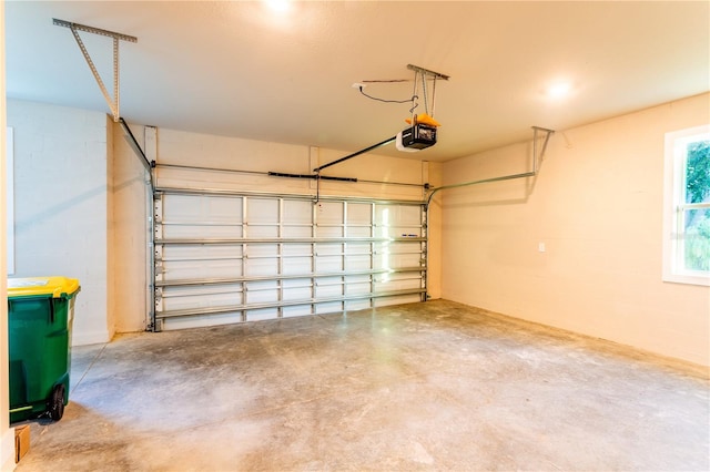 garage featuring concrete block wall and a garage door opener