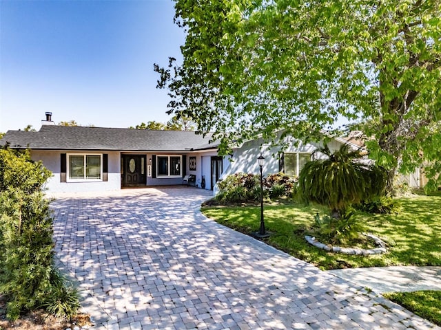 single story home featuring a front lawn and decorative driveway