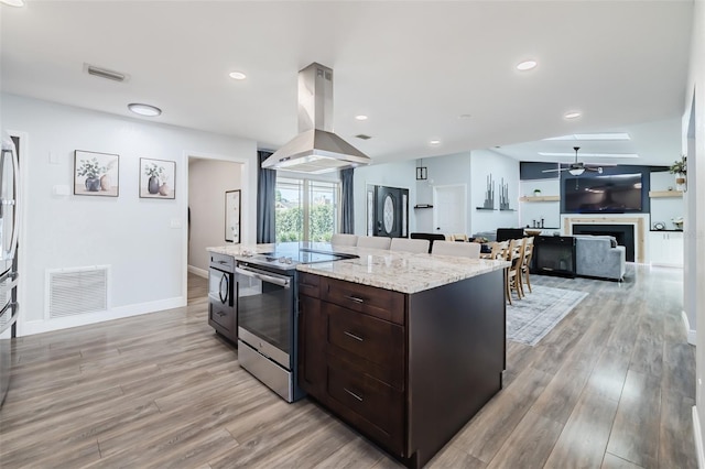 kitchen featuring visible vents, dark brown cabinets, stainless steel electric stove, island exhaust hood, and a ceiling fan