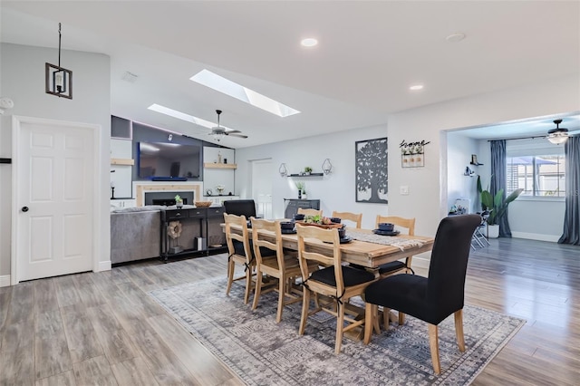 dining room with lofted ceiling with skylight, light wood finished floors, and ceiling fan