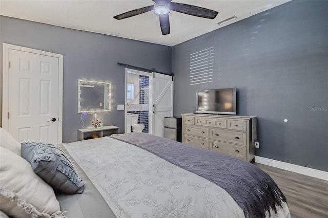 bedroom featuring visible vents, a ceiling fan, wood finished floors, a barn door, and baseboards