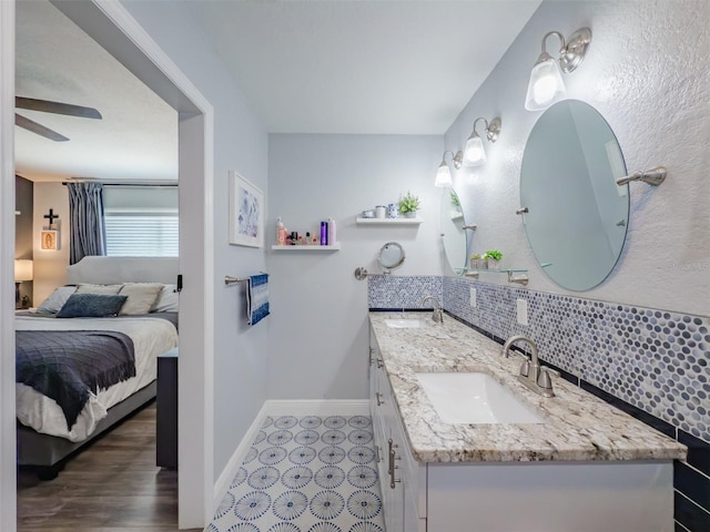 full bathroom featuring a sink, connected bathroom, baseboards, and decorative backsplash