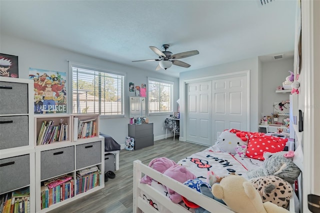 bedroom featuring visible vents, a ceiling fan, wood finished floors, a closet, and baseboards