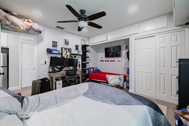 bedroom with visible vents, a closet, wood finished floors, and freestanding refrigerator