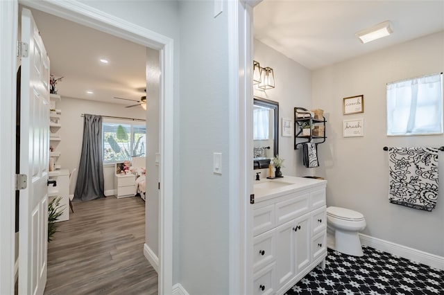 bathroom featuring toilet, wood finished floors, baseboards, ceiling fan, and vanity