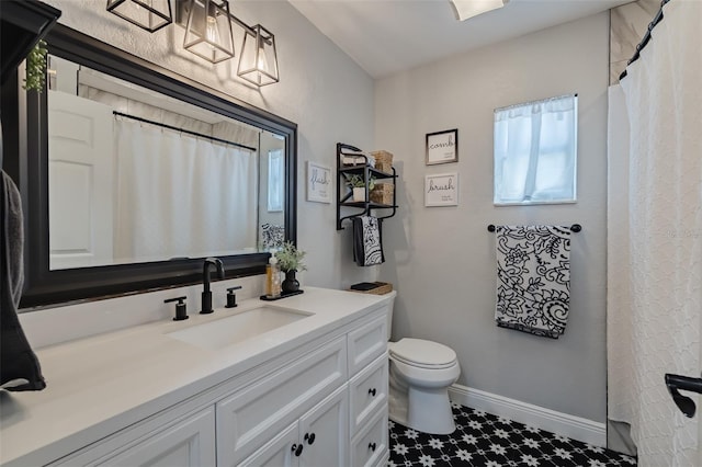 full bath featuring toilet, vanity, and baseboards