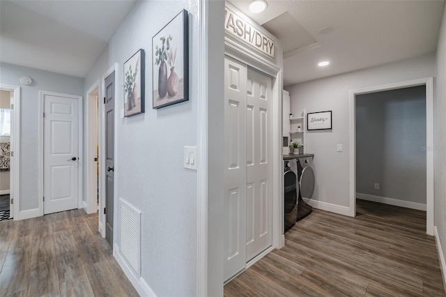 hallway featuring dark wood-style floors, separate washer and dryer, visible vents, and baseboards