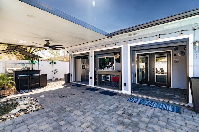 view of exterior entry with a patio area, a ceiling fan, and fence