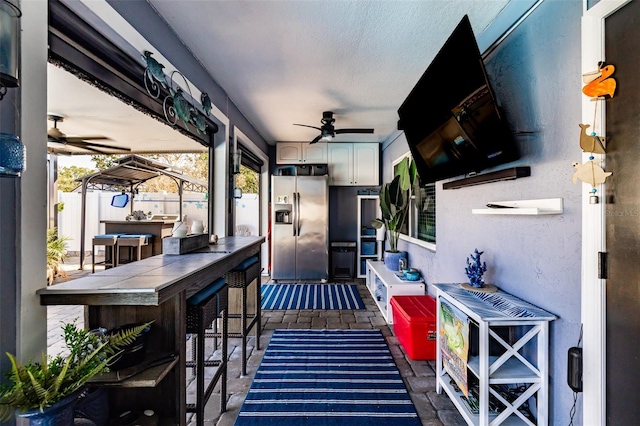 view of patio / terrace with a ceiling fan, fence, and outdoor dry bar