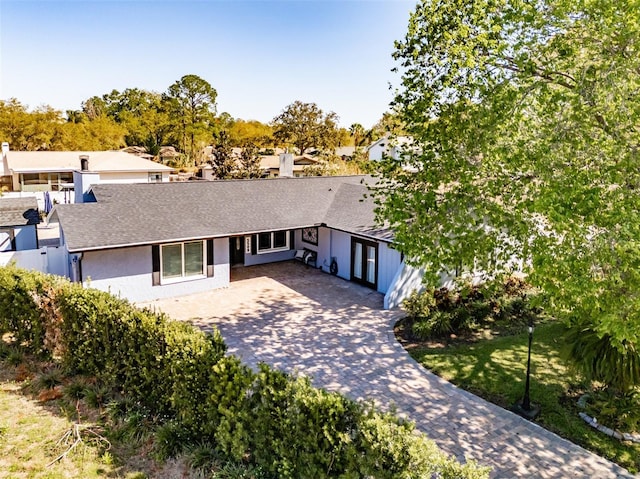 single story home featuring decorative driveway, roof with shingles, and stucco siding