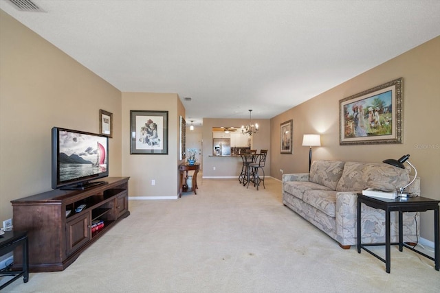 living room featuring visible vents, light carpet, baseboards, and a chandelier