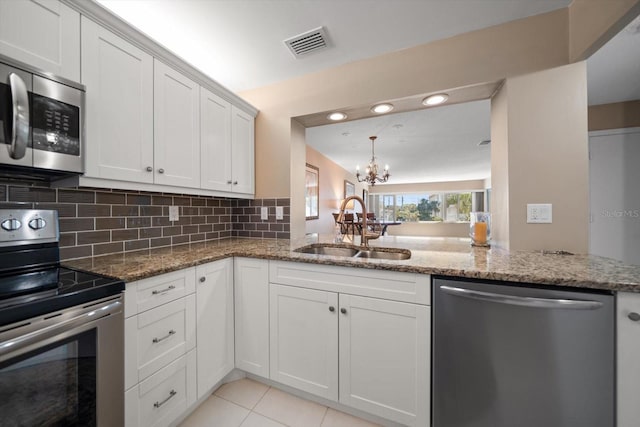 kitchen with tasteful backsplash, visible vents, an inviting chandelier, stainless steel appliances, and a sink