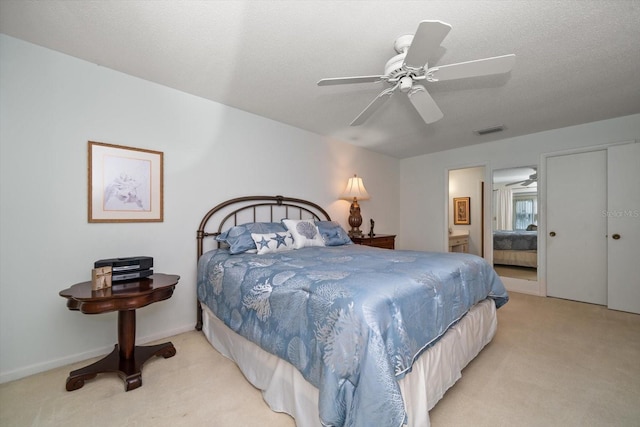 bedroom with visible vents, light colored carpet, a textured ceiling, and ensuite bathroom