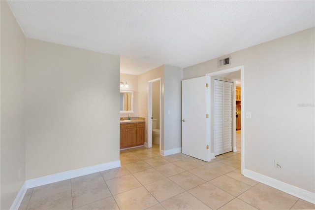 unfurnished bedroom featuring a textured ceiling, baseboards, and a sink