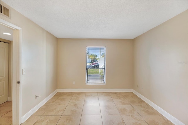 spare room featuring light tile patterned floors, visible vents, and a textured ceiling