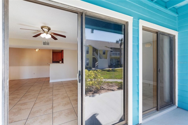 exterior space with light tile patterned flooring, wainscoting, visible vents, and ceiling fan