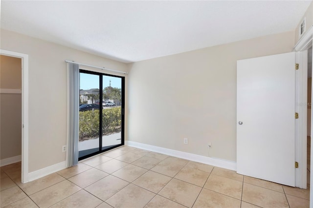 unfurnished room with light tile patterned flooring and baseboards